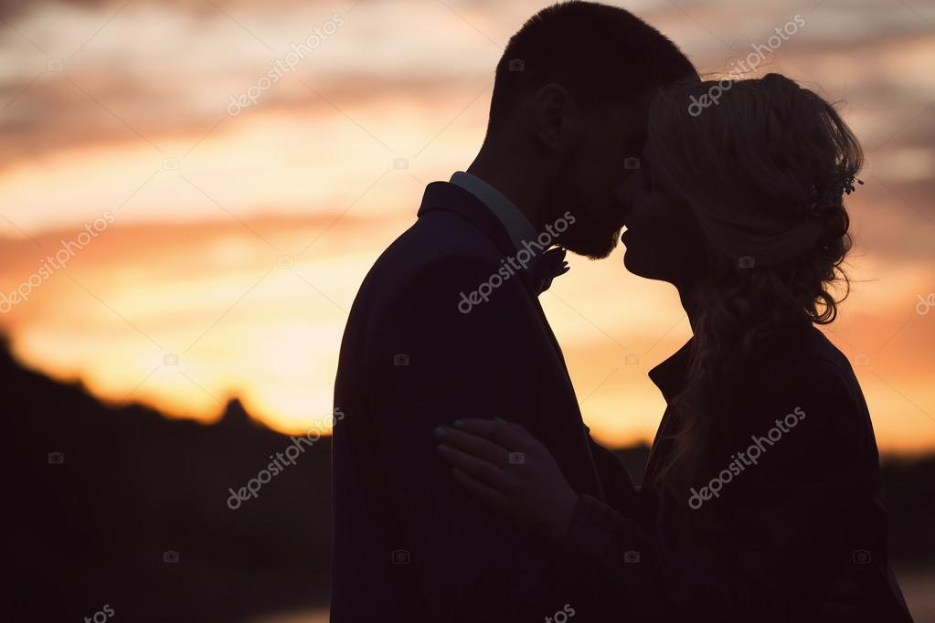 Жених и невеста целуются на закате — Стоковое фото