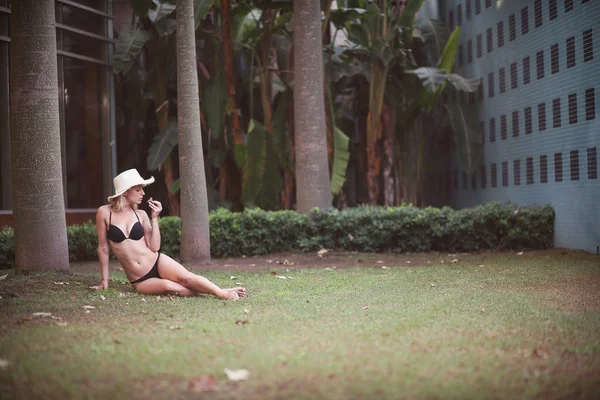 Дівчина в купальнику і капелюх, що сидить на траві — стокове фото