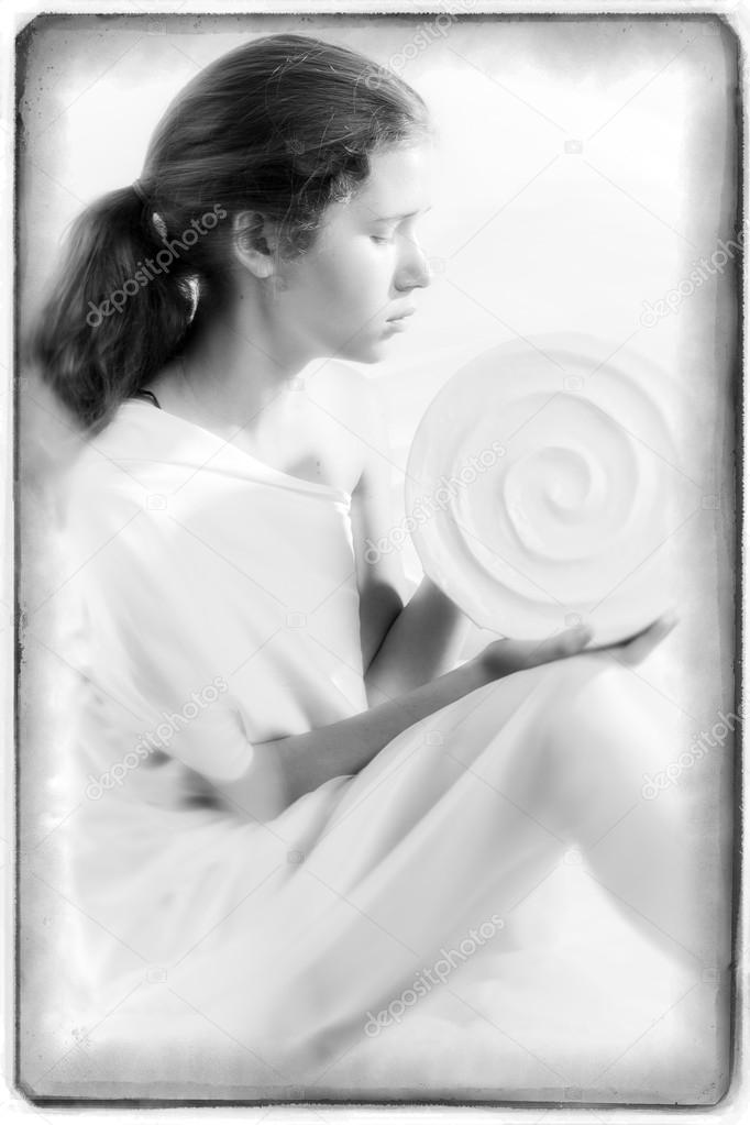 Pretty young girl sitting in profile and holding a round white vase
