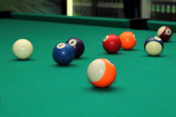 Більярдні кульки на зеленому столі і помаранчевий м'яч — стокове фото