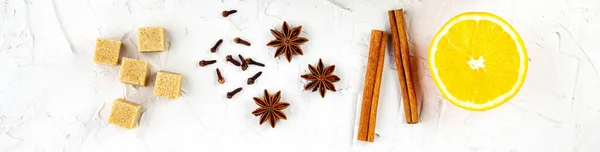 border of spice on white background. Ingredients for a mulled wine. Cinnamon, anise stars, orange, brown sugar, cloves. Christmas hot drink