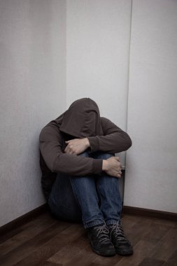 Kapüşonlu ve köşede yalnız oturan umutsuz bir uyuşturucu bağımlısı. Üzüntü, depresyon ve hayat sorunları kavramı
