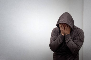 Gri başlıklı genç bir adamın portresi elleriyle yüzünü kapladı. Bağımlılık, alkolizm, depresyon ve umutsuzluk kavramı.