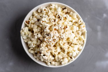 Gri masada beyaz kasede patlamış mısır. Kopyalama alanı olan üst görünüm