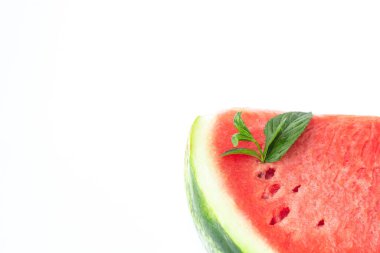 Beyaz arka planda yeşil nane yapraklı taze kırmızı olgun karpuz dilimlenmiş.