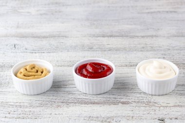 Beyaz ahşap arka planda üç çeşit klasik sos. Mayonez ketçap hardalı. Kopyalama alanı olan üst görünüm