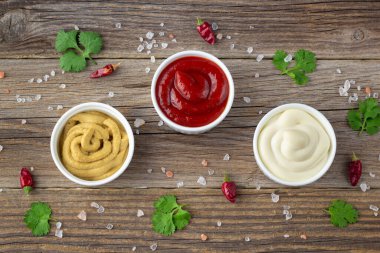Doğal ahşap arka planda baharatlı çeşitli soslar. Mayonez ketçap hardalı. Kopyalama alanı olan üst görünüm