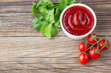 Maydanoz ve domates soslu beyaz kase. Doğal ahşap arka planda ketçap. Boşluğu ve üst görünümü kopyala