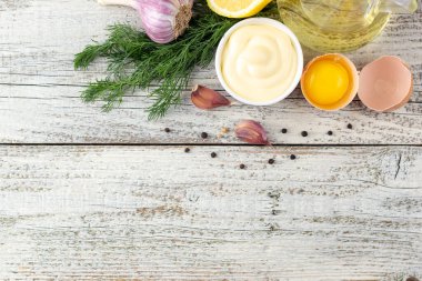 Beyaz ahşap arka planda sarımsak, yumurta, yağ, limon ve otlu mayonez sosu.