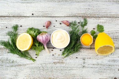 Sarımsak sosunun içeriği. Beyaz ahşap arka planda mayonez hazırlamak için ürünler. Kopyalama alanı olan üst görünüm