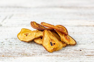 Beyaz ahşap arka planda dilimlenmiş kuru armut yığını. Kurutulmuş meyve cipsi. Sağlıklı vejetaryen yemekleri.