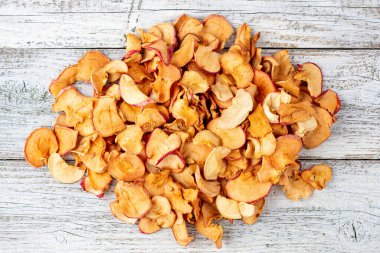 Beyaz ahşap arka planda dilimlenmiş kurumuş elma yığını. Kurutulmuş meyve cipsi. Sağlıklı yiyecekler. Üst görünüm