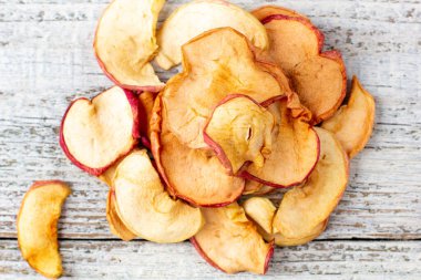 Beyaz ahşap arka planda dilimlenmiş kurumuş elma yığını. Kurutulmuş meyve cipsi. Sağlıklı yiyecekler. Üst görünüm