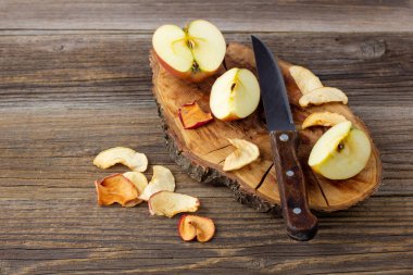 Ahşap zemin üzerinde kurumuş elma ve taze olgun elmalar yığını. Kurutulmuş meyve cipsi. Sağlıklı vejetaryen yemekleri