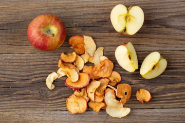 Ahşap zemin üzerinde kurumuş elma ve taze olgun elmalar yığını. Kurutulmuş meyve cipsi. Sağlıklı vejetaryen yemekleri