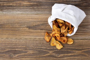 Ahşap arka plandaki beyaz bir keseden bir yığın kurutulmuş armut hapı. Kurutulmuş meyve cipsi. Sağlıklı vejetaryen yemekleri