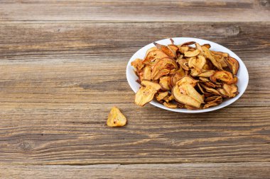 Ahşap arka planda beyaz bir tabakta dilimlenmiş kuru armut yığını. Kurutulmuş meyve cipsi. Sağlıklı yiyecekler. Kopyalama alanı ile