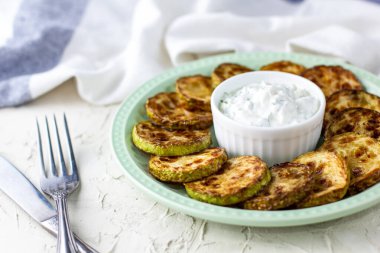 Ekşi krema soslu kızarmış kabak dilimleri. Beyaz arka planda akşam yemeği için otlu kızarmış kabaklar ve peçete.