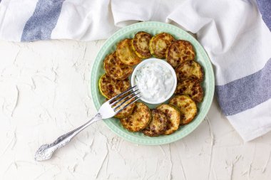 Ekşi krema soslu kızarmış kabak dilimleri. Beyaz arka planda akşam yemeği için otlu kızarmış kabaklar. Kopyalama alanı olan üst wiev
