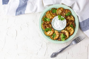 Ekşi krema soslu kızarmış kabak dilimleri. Beyaz arka planda akşam yemeği için otlu kızarmış kabaklar. Kopyalama alanı olan üst wiev