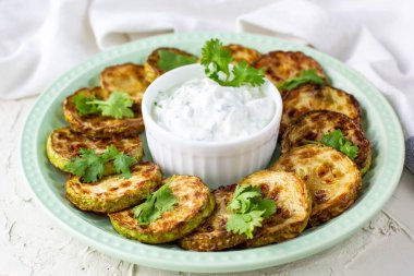 Ekşi krema soslu kızarmış kabak dilimleri. Beyaz arka planda akşam yemeği için otlu kızarmış kabaklar. Üst Wiev