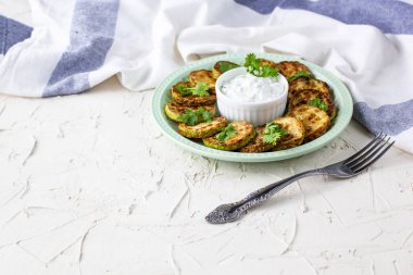 Ekşi krema soslu kızarmış kabak dilimleri. Beyaz arka planda akşam yemeği için otlu kızarmış kabaklar. Üst Wiev