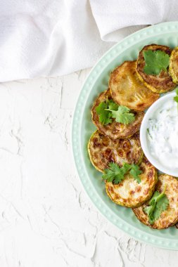 Ekşi krema soslu kızarmış kabak dilimleri. Beyaz arka planda akşam yemeği için otlu kızarmış kabaklar. Üst Wiev