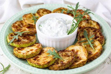 Ekşi krema soslu kızarmış kabak dilimleri. Beyaz arka planda akşam yemeği için otlu kızarmış kabaklar. Üst Wiev