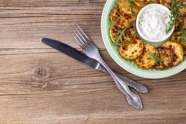 Ekşi krema soslu kızarmış kabak dilimleri. Doğal kahverengi ahşap arka planda akşam yemeği için otlu kızarmış kabaklar. Kopyalama alanı olan üst wiev