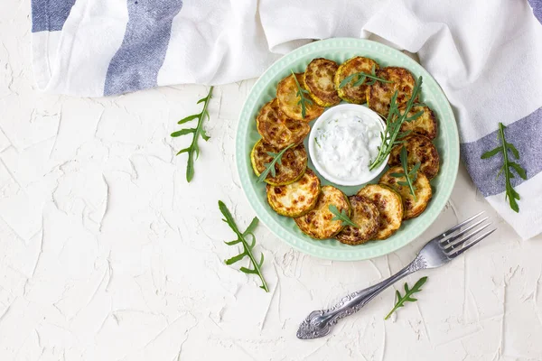 Ekşi krema soslu kızarmış kabak dilimleri. Beyaz arka planda akşam yemeği için otlu kızarmış kabaklar. Kopyalama alanı olan üst wiev