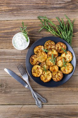 Ekşi krema soslu kızarmış kabak dilimleri. Doğal kahverengi ahşap arka planda akşam yemeği için otlu kızarmış kabaklar. Üst Wiev