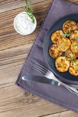 Ekşi krema soslu kızarmış kabak dilimleri. Doğal kahverengi ahşap arka planda akşam yemeği için otlu kızarmış kabaklar. Üst Wiev