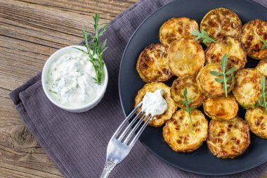 Ekşi krema soslu kızarmış kabak dilimleri. Doğal kahverengi ahşap arka planda akşam yemeği için otlu kızarmış kabaklar. Top wiev. Kapat.