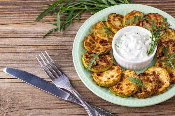 Ekşi krema soslu kızarmış kabak dilimleri. Doğal kahverengi ahşap arka planda akşam yemeği için otlu kızarmış kabaklar. Üst Wiev