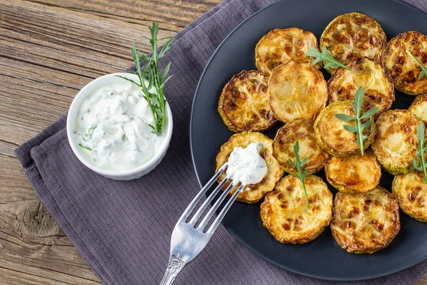 Ekşi krema soslu kızarmış kabak dilimleri. Doğal kahverengi ahşap arka planda akşam yemeği için otlu kızarmış kabaklar. Top wiev. Kapat.