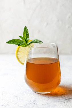 Çiğ mayalanmış ev yapımı alkolik ya da alkolsüz kombu çayı. Buzlu çay ve sağlıklı probiyotik bardakta limon dilimi ve beyaz arka planda nane.
