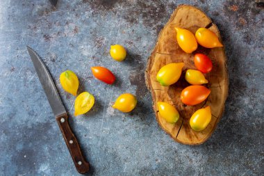 Kırsal mavi arka planda çeşitli renkli olgun domatesler. Sarı portakallı ve kırmızı domatesli pişirme. Üst görünüm