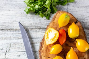 Beyaz ahşap arka planda çeşitli renkli olgun domatesler. Sarı portakallı ve kırmızı domatesli pişirme. Kopyalama alanı olan üst görünüm