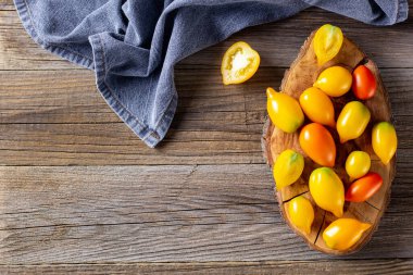 Ahşap zemin üzerinde çeşitli renkli olgun domates. Sarı portakallı ve kırmızı domatesli pişirme. Kopyalama alanı olan üst görünüm