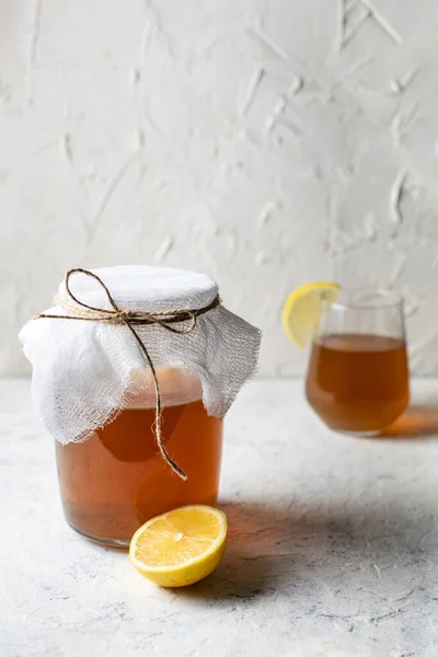 Raw fermented homemade alcoholic or non alcogolic kombucha superfood. Ice tea with healthy natural probiotic in glass with lemon slice on white background