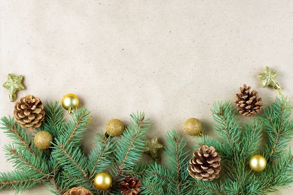 テキストのコピースペースを持つクリスマスカードのクラフト紙の上にコーンと金の装飾とモミの木の枝の境界 新年のコンセプト 休日の背景 クリスマスのモックアップ トップビュー フラットレイアウト — ストック写真