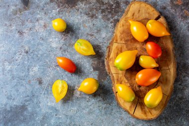 Kırsal mavi arka planda çeşitli renkli olgun domatesler. Sarı portakallı ve kırmızı domatesli pişirme. Üst görünüm