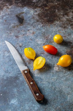 Kırsal mavi arka planda çeşitli renkli olgun domatesler. Sarı turuncu ve kırmızı domatesleri bıçakla pişirmek.