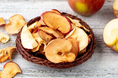 Ahşap zemin üzerinde kurumuş elma ve taze olgun elmalar yığını. Kurutulmuş meyve cipsi. Sağlıklı vejetaryen yemekleri