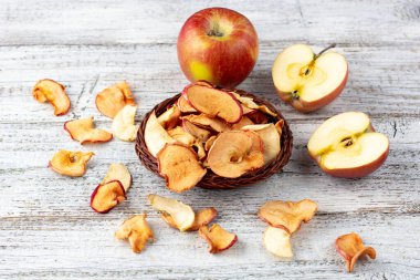 Ahşap zemin üzerinde kurumuş elma ve taze olgun elmalar yığını. Kurutulmuş meyve cipsi. Sağlıklı vejetaryen yemekleri