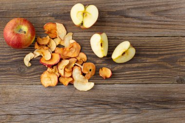Ahşap zemin üzerinde kurumuş elma ve taze olgun elmalar yığını. Kurutulmuş meyve cipsi. Sağlıklı vejetaryen yemekleri