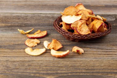 Tahta arka planda hasır sepette kurumuş elma dilimleri yığını. Kurutulmuş meyve cipsi. Sağlıklı yiyecekler. Üst görünüm