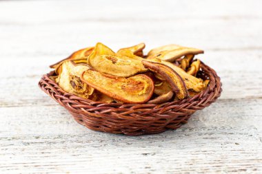 Beyaz ahşap arka planda hasır sepette kurumuş armut dilimleri yığını. Kurutulmuş meyve cipsi. Sağlıklı vejetaryen yemekleri.