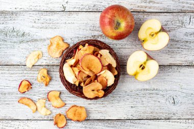 Ahşap zemin üzerinde kurumuş elma ve taze olgun elmalar yığını. Kurutulmuş meyve cipsi. Sağlıklı vejetaryen yemekleri