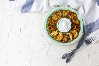 Ekşi krema soslu kızarmış kabak dilimleri. Beyaz arka planda akşam yemeği için otlu kızarmış kabaklar. Kopyalama alanı olan üst wiev